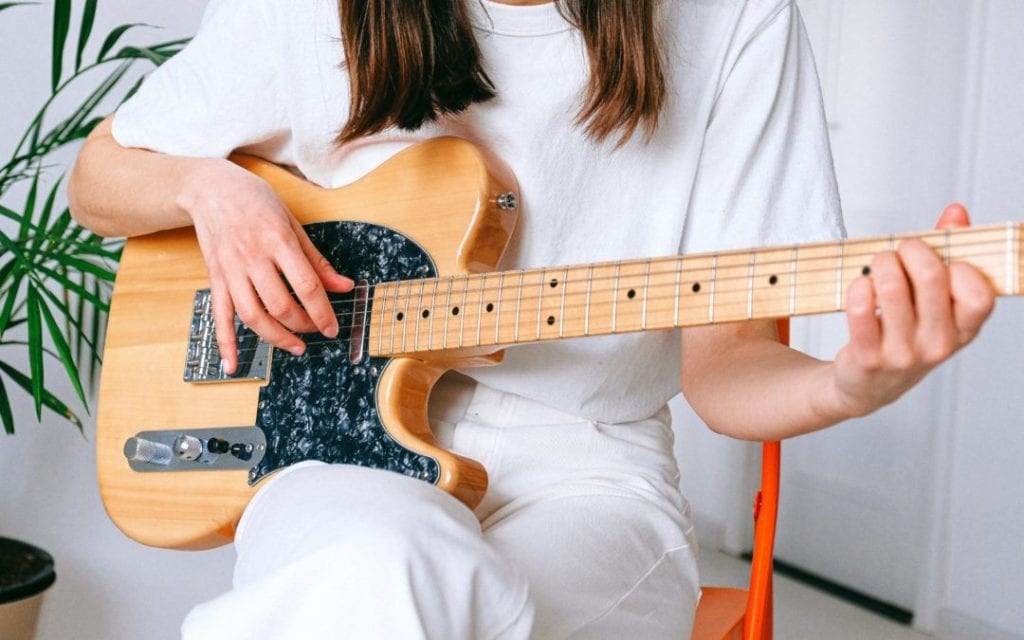 woman in white shirt playing the guitar